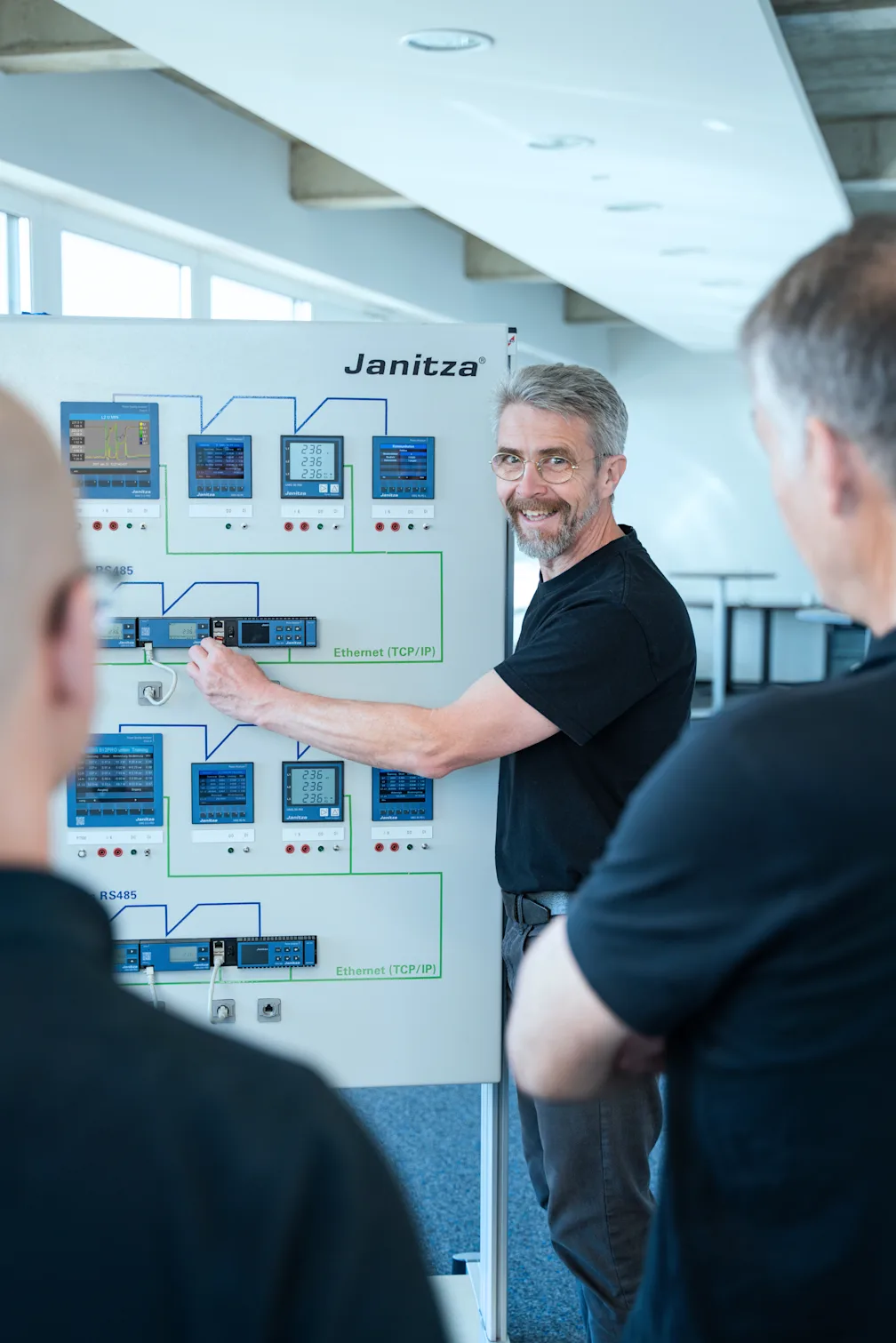 Trainer erklärt einem Team das Energiemanagement mit Hilfe eines Janitza-Schulungsmoduls