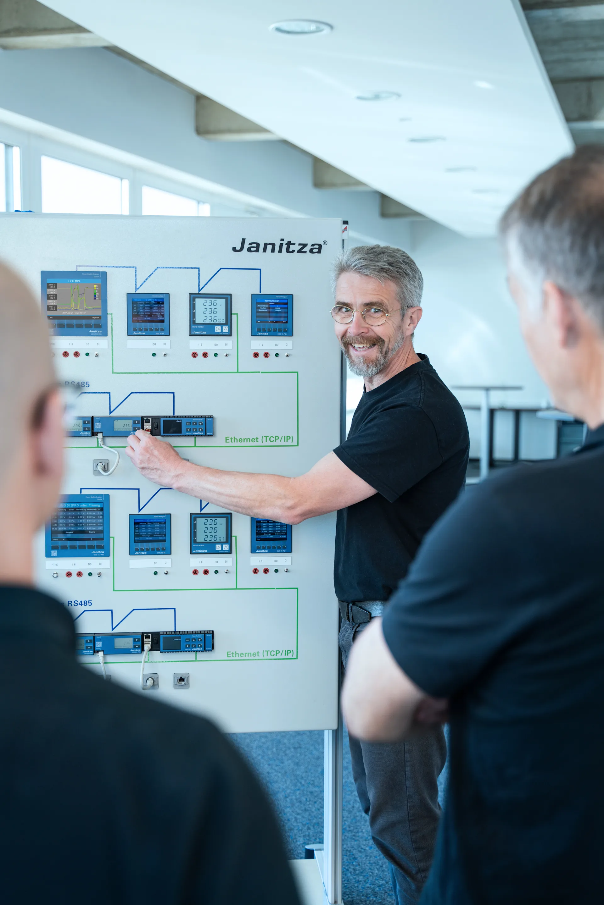 Trainer erklärt einem Team das Energiemanagement mit Hilfe eines Janitza-Schulungsmoduls