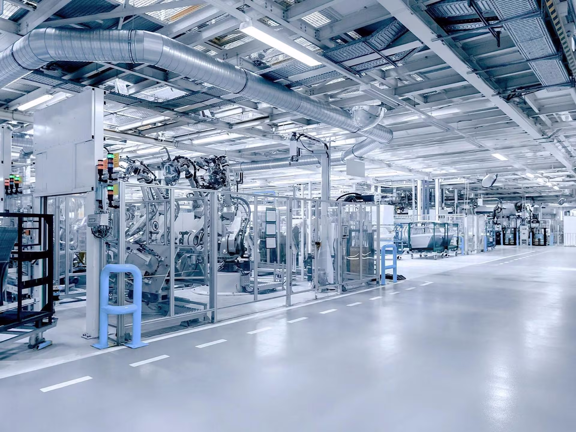 Große industrielle Fertigungshalle mit automatisierten Maschinen, Robotern und Belüftungssystemen, die eine moderne Produktionsumgebung zeigen.